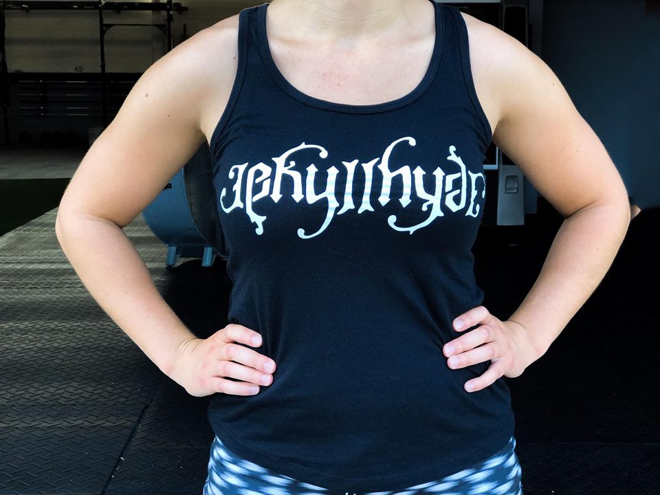 Muscular woman wearing a black tank top with Jekyllhyde across the chest in white print. 