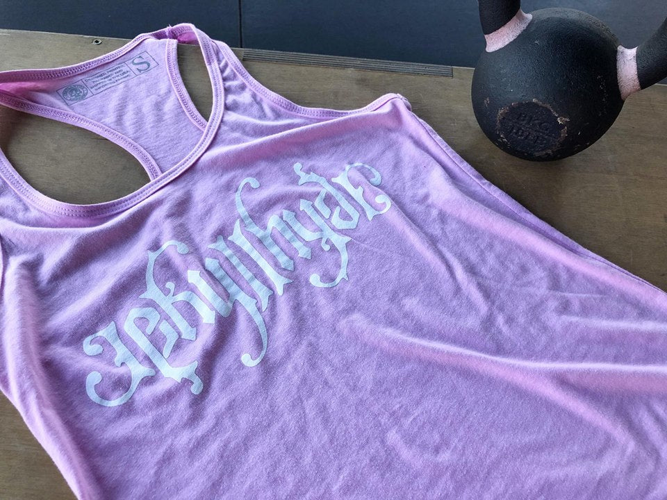 Pink tank top laying next to a kettlebell with Jekyllhyde printed on the front. 
