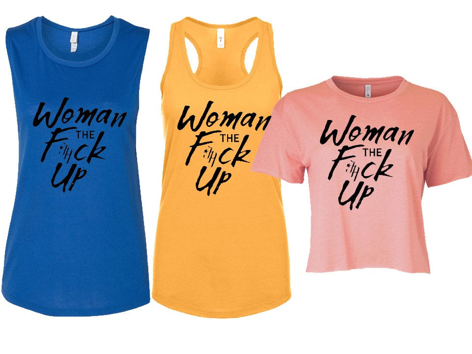 Three women's clothing items in blue, yellow, and pink colors, each with the phrase 'Woman the F*ck Up' printed on them. The clothing items are a muscle tee, a tank top, and a crop top.
