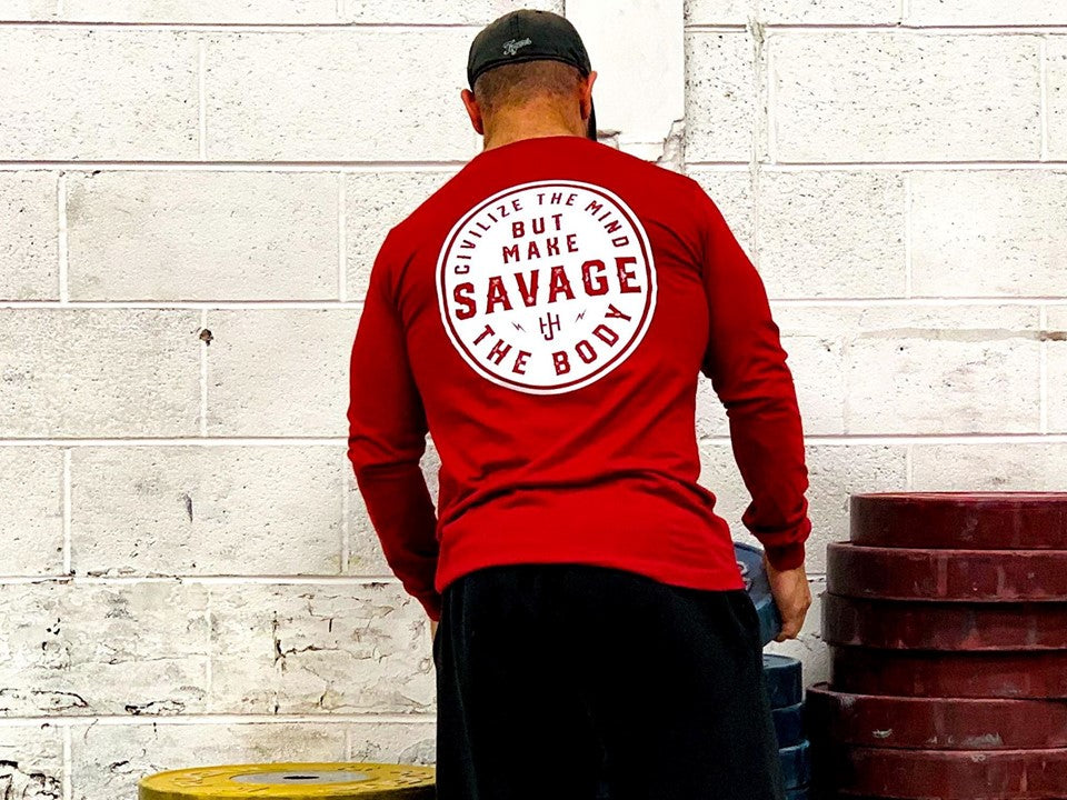 Man picking up weight plates in a red long sleeve. 