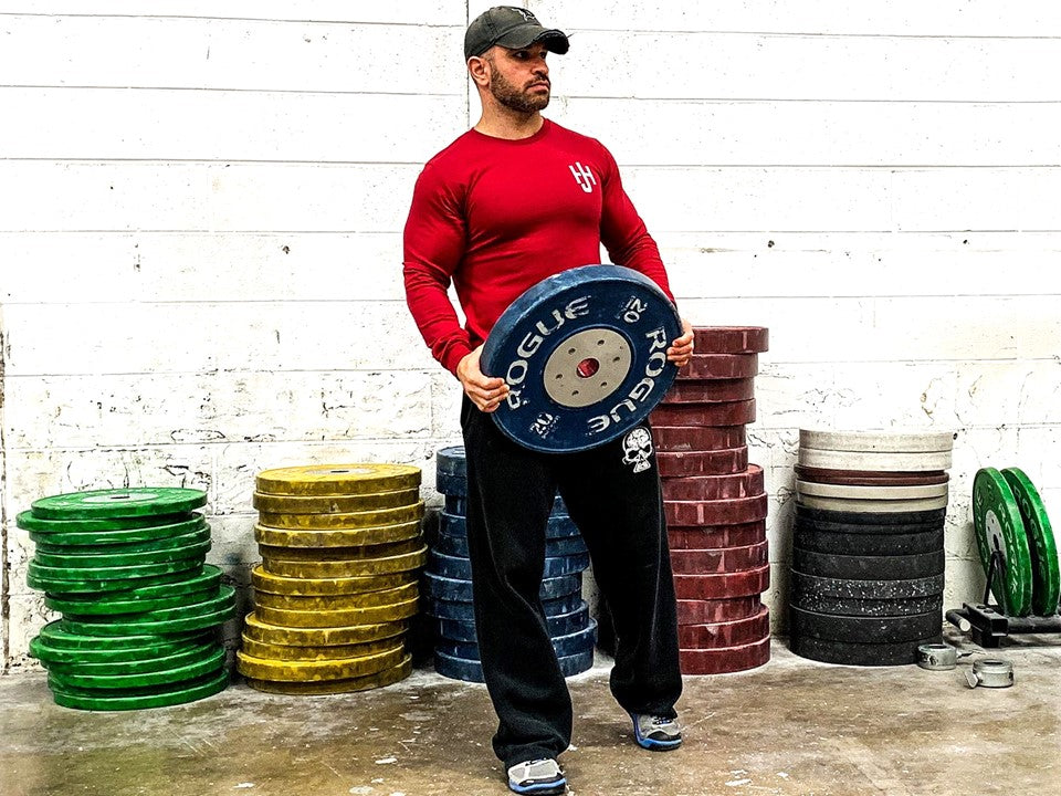 Man holding a weight plate in red long sleeve shirt. 