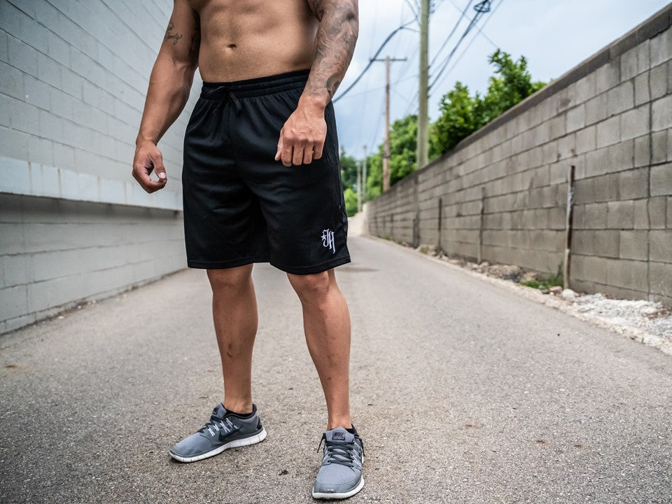 Black shorts on a muscular man standing in an alley. 
