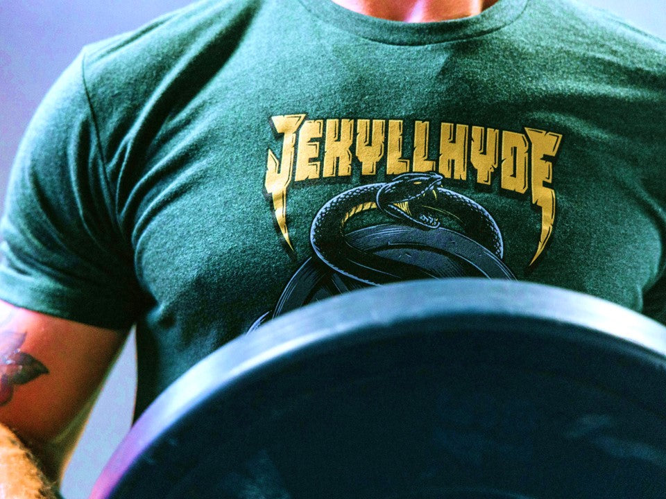 The shoulders of a man holding a weight in green shirt with a snake on it. 