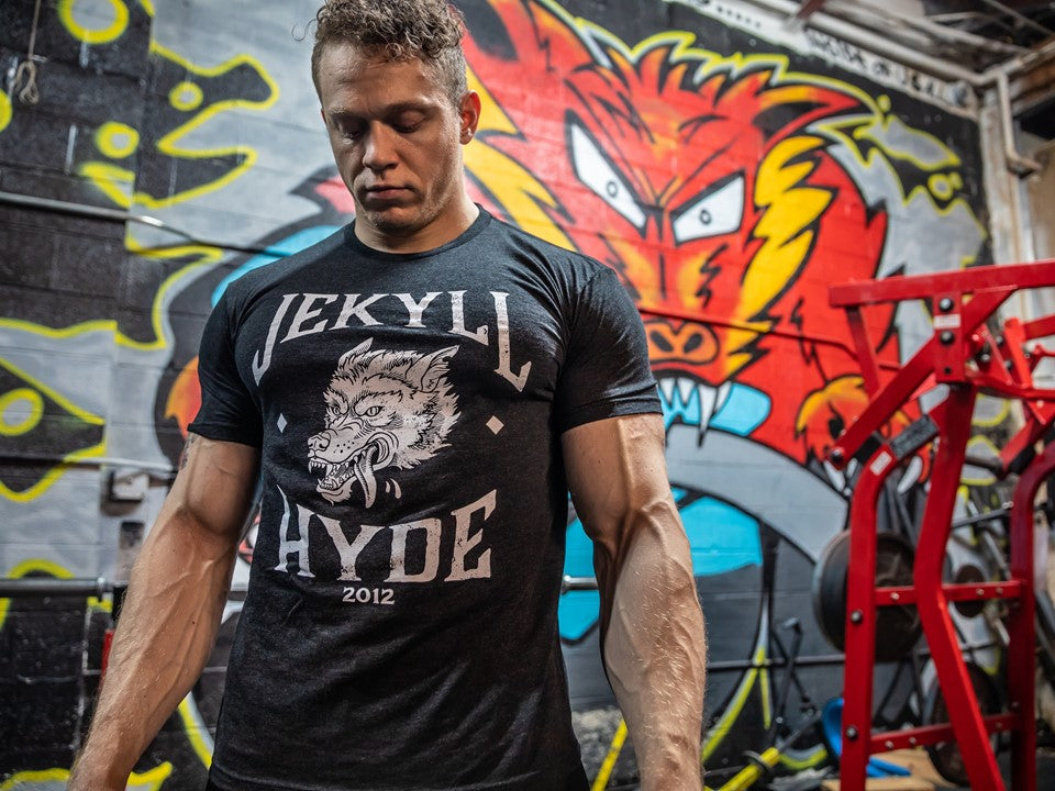 Man standing in front of a mural wearing a black shirt with a wolf on it. 